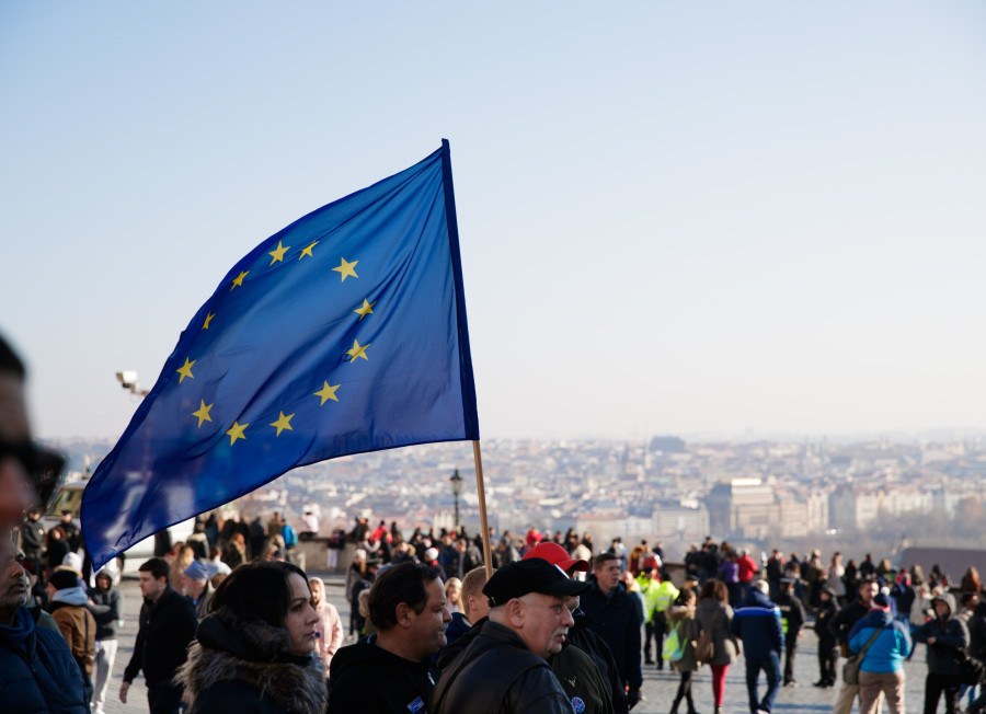 Bild einer Demonstration. Im Fokus steht eine EU Flagge, die im Wind weht